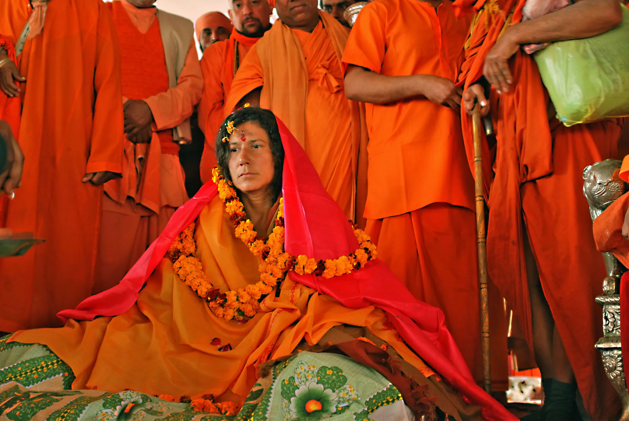 Mataji Shaktiananda con velo rosso seduta tra swami vestiti d’arancione al Kumbha Mela