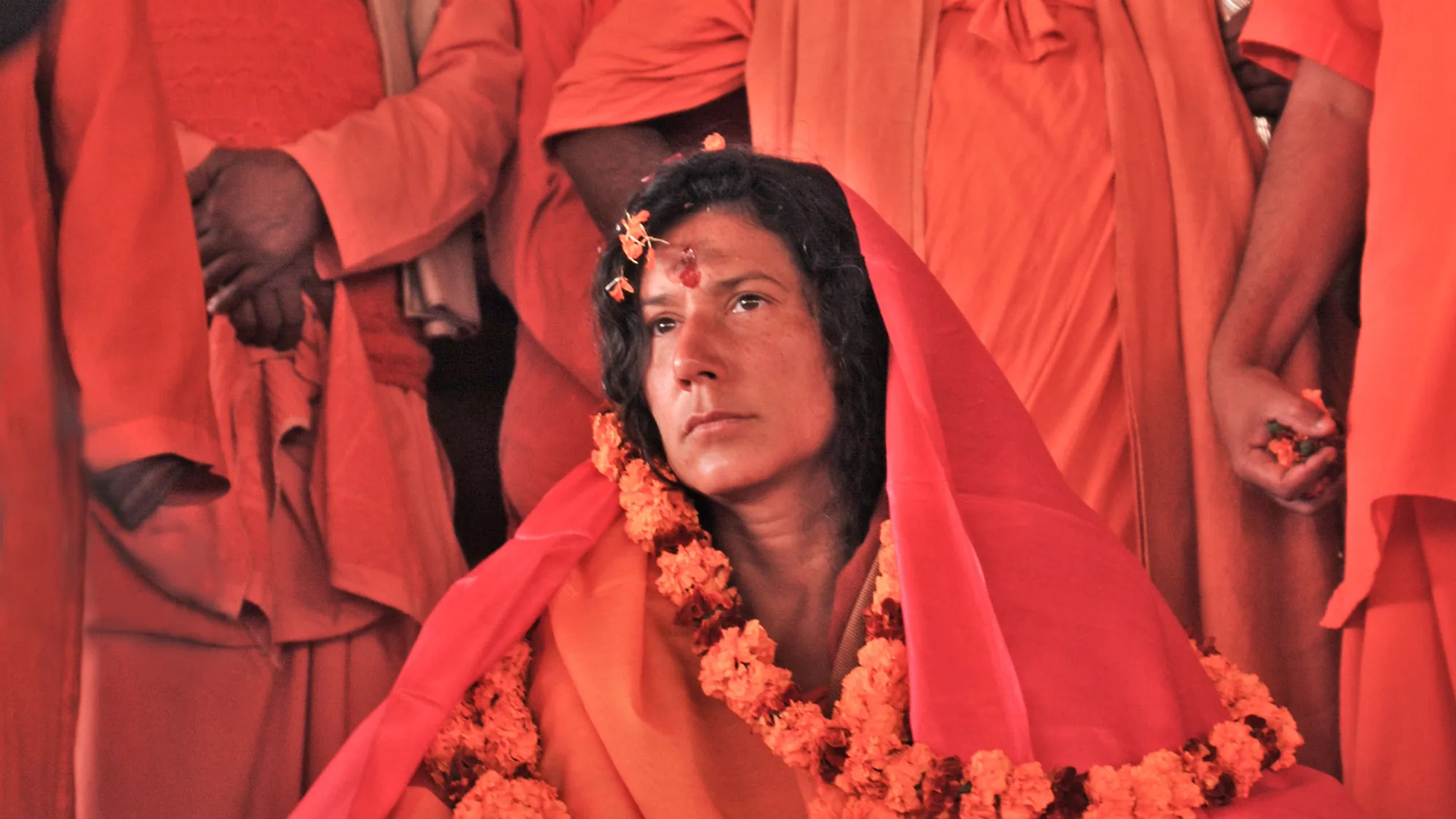 Mataji Shaktiananda with a red veil and an orange garland among swamis