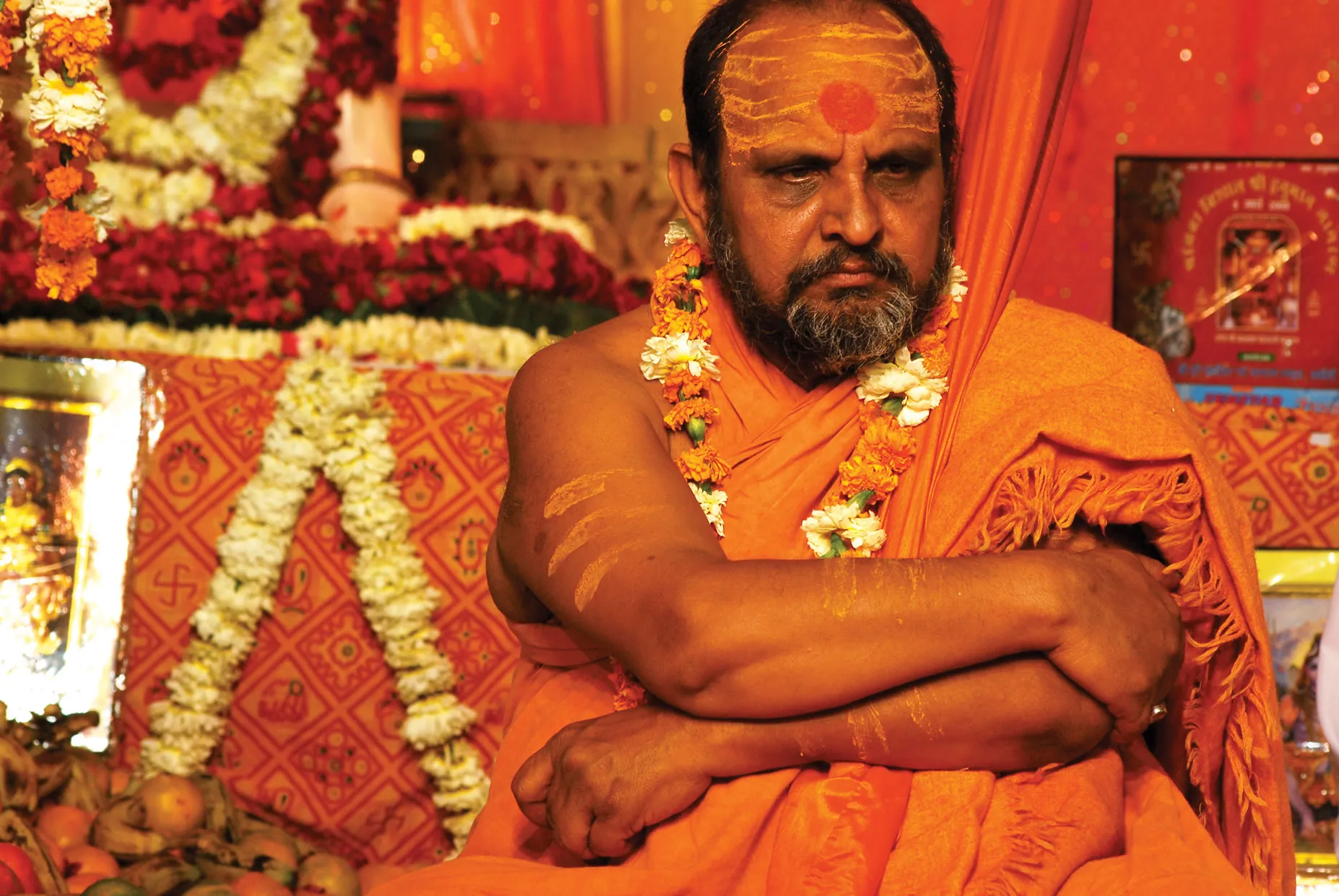 Swami Divyanand seated, adorned with garlands